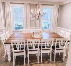 a dining room table with white chairs and a chandelier