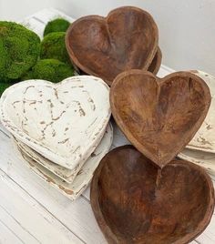 three heart shaped wooden bowls sitting on top of a white table next to broccoli