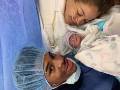 a man and woman in hospital gowns are looking at the camera while holding their baby