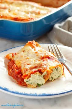 a slice of lasagna on a plate with a fork and casserole dish in the background