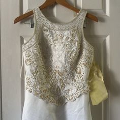 a white dress hanging on a hanger in front of a door with a yellow ribbon