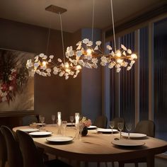 a dining room table with plates and wine glasses on it, surrounded by hanging lights