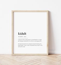 a white framed poster with the words kiddut in black on it, sitting against a wall