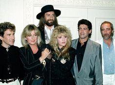 a group of people standing next to each other in front of a white wall and door