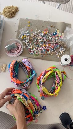 a person is making bracelets on a table with beads and spools of thread