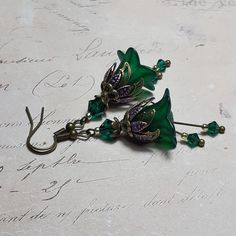 EMERALD FLOWER EARRINGS  ▪️▪️▪️▪️▪️▪️▪️️▪️▪️▪️▪️▪️▪️ These pretty emerald green floral earrings are made with super cute Lucite fairy flowers which have been hand painted with an iridescent finish. They have Swarovski crystals in beautiful emerald green added for sparkle when they move and are finished with fish hook ear wires and ornate floral bead caps. They are very light weight and are perfect for special occasions, festivals and bridesmaids yet cute enough for everyday wear.  💜A matching p