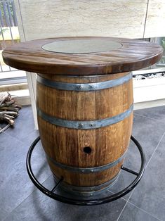 a wooden barrel table with glass top sitting on a tile floor in front of a window