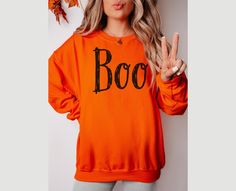 Boo Sweatshirt Women Halloween Crew Neck Black Boo Sweatshirt Spooky Season Shirt Halloween Party Pullover Ghost Sweater Fall Gift for Her Fall Crewneck  SIZE UP for OVERSIZED FIT 👻Boo Tshirt - https://beealleydesign.etsy.com/listing/1776554963 CREWNECK SWEATSHIRTS: -Gildan sweatshirts -50% cotton, 50% polyester -Medium-heavy fabric  -Ribbed Knit collar with seam helps retain its shape -Classic loose fit -sewn-in label All Shirts are made to order.  They will ship within one week from one of ou Halloween Crew Neck Sweater, Spooky Orange Long Sleeve Tops, Orange Long Sleeve Spooky Top, Casual Halloween Crew Neck Sweater, Casual Halloween Sweater With Crew Neck, Casual Crew Neck Halloween Sweater, Casual Crew Neck Sweater For Halloween, Spooky Long Sleeve Sweatshirt For Fall, Orange Crew Neck Halloween Sweatshirt