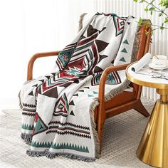 a chair with a blanket on top of it next to a table and potted plant