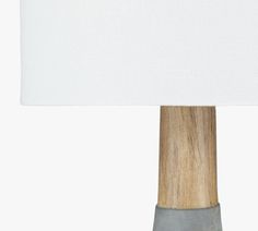 a wooden table lamp with a white shade on the top and grey base, against a white background