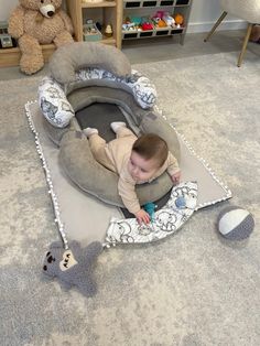 a baby laying on top of a blanket next to a teddy bear