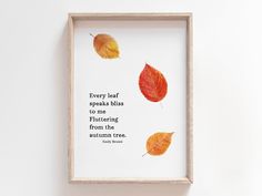 there is a framed photo with some leaves on the wall and a quote about autumn