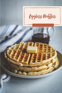 two waffles on a plate with butter and syrup in the background, next to a cup of coffee