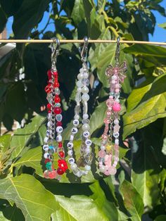 several necklaces hanging from a tree with leaves in the background