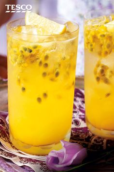 two glasses filled with yellow liquid and topped with lemon