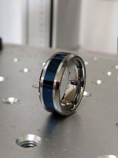 a blue and silver ring sitting on top of a metal table with holes in it