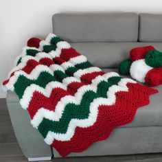 a couch with a blanket on it and two balls of yarn next to it