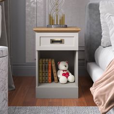 a white teddy bear sitting on top of a book shelf next to a night stand