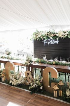 the reception table is decorated with greenery and gold letters that spell out the word love