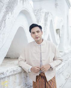 a man standing in front of a white wall with his hands on his hips and looking at the camera