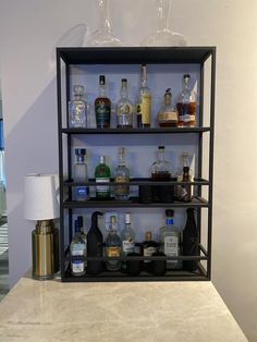 a shelf filled with bottles and glasses on top of a counter next to a lamp