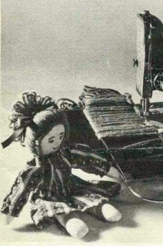 an old fashioned doll sitting next to a sewing machine