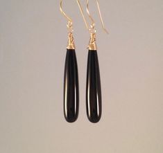 Beautiful, long, smooth black onyx drops wire wrapped in 14K gold fill.  These stones are long and elegant.  They are wire wrapped in 14k gold fill, and finished with my hand forged 14k gold fill ear wires.  These are also available in sterling silver. Length from top of ear wire:  2 inches Black Onyx Gemstones:   approximately 35 mm long, 6 mm wide at bottom Ear Wires: 14K gold filled, hand forged by me  Please note: these earrings are made to order, so there will be slight variations in stone size by 1-2 mm, not a noticeable difference. All of my jewelry is designed and handcrafted by me.  I love to experiment with different designs and although I may make similar designs more than once, each piece of jewelry is truly one of a kind due to variations between gemstones and within my own cr Black Earring, Black Onyx Earrings, Onyx Earrings, Earrings Long, Black Earrings, Gold Wire, Wire Wrap, Gold Gold, Elegant Gift