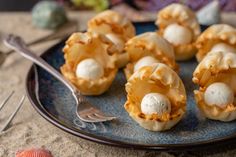 small shells with eggs in them on a blue plate next to a fork and spoon