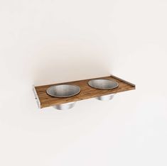 two metal bowls on a wooden shelf against a white wall