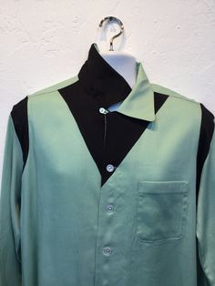 "1950s vintage reproduction Hollywood Rogue two tone mint green and black shirt The shirt has a two tone design with mint green and contrasting black on shoulders and neckline. The garment has a loop collar, five button down front, one patch pocket and long sleeves. The label reads \"Hollywood Rogue\" and the shirt is in new unworn condition. As with all clothes made by \"Hollywood Rogue\" this shirt was made in an original 1950's design and is only available in very limited numbers. Made in Cal Retro Black Tops With Buttons, Black Retro Tops With Buttons, Black Retro Top With Buttons, Retro Black Collared Shirt, Retro Black Tops With Button Closure, Retro Black Long Sleeve Shirt, Retro Black Tops For Work, Retro Black Button-up Shirt, Retro Green Button-up Top