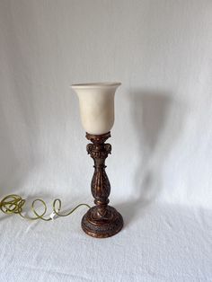 a white vase sitting on top of a wooden stand next to a corded telephone