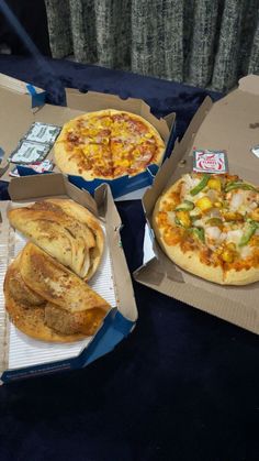 three pizzas in boxes with different toppings sitting on a table next to each other