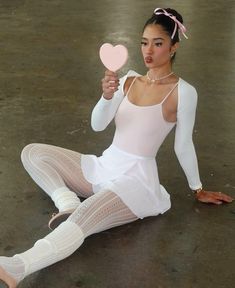 a woman sitting on the ground holding a heart shaped object