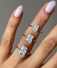 a woman's hand with three engagement rings on it