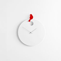 a white clock with a red bird on it