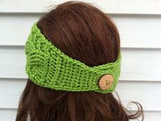 a woman wearing a green headband with a wooden button on it's side