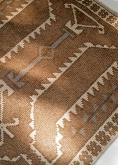 a brown and white rug on the floor with light coming in from it's window