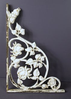 an ornate white iron shelf with flowers and leaves on the top, against a gray background