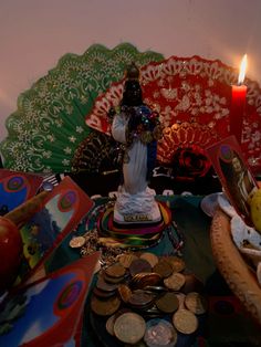 a table topped with lots of assorted items and a lit candle in the background