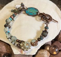 This boho bracelet is pretty and perfect with any summer outfit! Made is shades of aqua and accented with a real seashell, glass, ceramic, gemstone and copper metal beads with a toggle clasp. Measures 7 1/2 inches. Bohemian Bracelets With Lobster Clasp For Beach, Bohemian Czech Glass Bracelets For Beach, Bohemian Czech Glass Beaded Bracelets For Beach, Shades Of Aqua, Bracelets Handmade Diy, Beachy Boho, Multi Strand Bracelet, Boho Bracelet, Bracelet Ideas