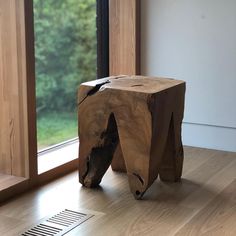 a wooden stool sitting on top of a hard wood floor in front of a window