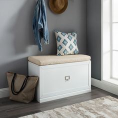 a white bench sitting in front of a window next to a purse and coat rack