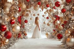 a woman standing in front of a christmas tree with red and gold ornaments on it