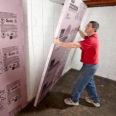 a man holding up a large poster in front of a white wall with instructions on it