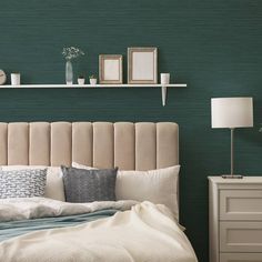 a bedroom with green walls and white bedding, two framed pictures on the wall