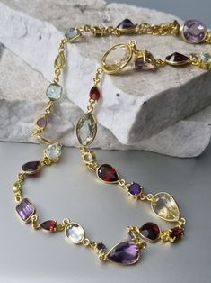 A sublime collection of gemstones forms this gorgeous piece. All set in 14k gold vermeil, on top of 925 silver. NO BRASS There are a total of 34 stones in Amethysts, Citrines, Garnets, Blue Topaz, Tanzanites. All in varying sizes and varying cuts. The largest measures 15mm x 8mm, smallest 5mm. Length of necklace is 18 inches with a further 3/4" of extension chain. Formal Multi-stone Amethyst Necklaces, Formal Amethyst Multi-stone Necklace, Formal Multi-stone Amethyst Necklace, Luxury Amethyst Multi-stone Necklace, Luxury Multi-stone Amethyst Necklace, Faceted Gold Amethyst Gemstones, Oval Amethyst Multi-stone Necklaces, Amethyst Oval Multi-stone Necklace, Oval Amethyst Multi-stone Necklace