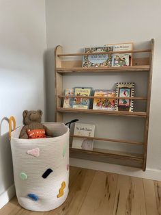 a teddy bear sitting in a basket next to a book shelf with books on it