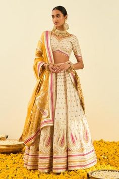 Daisy white pure raw silk lehenga with gotapatti and highlighted with basra moti. Paired with a embroidered blouse and a mustard silk organza dupatta.
Component: 3
Pattern: Embroidered
Type Of Work: Floral, Paisley
Neckline: Leaf
Sleeve Type: Short Sleeves
Fabric: Lehenga and Blouse - Raw Silk; Dupatta - Silk Organza
Color: White
Other Details: 
Gota and bead work
Embroidered dupatta
Tassel detail
Occasion: Wedding,Bride - Aza Fashions Sheetal Batra, Bridal Lehenga Images, Lehenga Images, Lehenga And Blouse, Bridal Lehenga Online, Designer Bridal Lehenga Choli, Raw Silk Lehenga, Lehenga Choli Wedding, Bridal Lehenga Collection