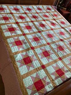 a bed with a quilt on top of it next to a wooden headboard and night stand