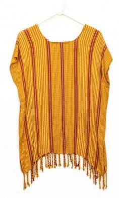 This light weight, soft blouse was hand-woven using 100% Cotton, Hilo Aleman. It is a versatile and vibrant piece that comes in a range of deep blue, red, and yellow shades. Each top features tassels that decorate and enriches each blouse. The striped pattern of this top is simple and subtle, yet the tassels add a flowy addition, which gives it motion and character. DETAILS Material: 100% Cotton, Hilo AlemaniaSize: 29.9" length x 18.5" - 76cm length x 47cm widthCare: Hand-wash in cold water, tre Casual Tunic Top With Tassels, Bohemian Striped Cotton Tops, Red Fringe Tops For Summer, Bohemian Striped Tops For Vacation, Summer Cotton Fringe Blouse, Summer Cotton Blouse With Fringe, Bohemian Cotton Blouse With Fringe, Cotton Beach Tops With Tassels, Casual Red Tops With Tassels